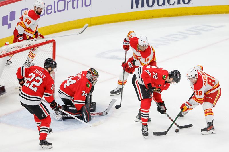 Mar 26, 2024; Chicago, Illinois, USA; Chicago Blackhawks defenseman Alex Vlasic (72) battles for the puck with Calgary Flames left wing Andrew Mangiapane (88) during the second period at United Center. Mandatory Credit: Kamil Krzaczynski-USA TODAY Sports