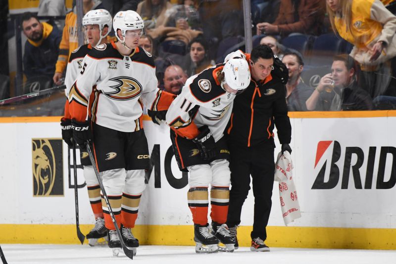 Jan 9, 2024; Nashville, Tennessee, USA; Anaheim Ducks center Trevor Zegras (11) is helped off the ice after an injury first period against the Nashville Predators at Bridgestone Arena. Mandatory Credit: Christopher Hanewinckel-USA TODAY Sports