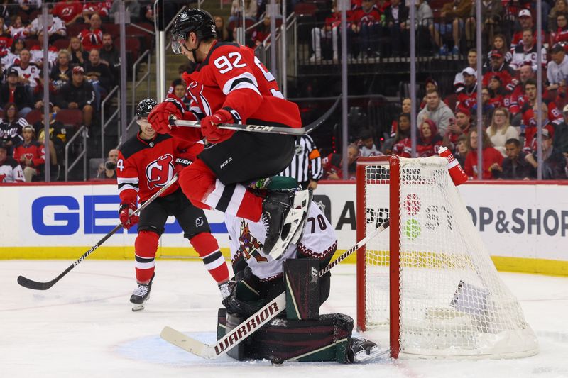 Oct 13, 2023; Newark, New Jersey, USA; Arizona Coyotes goaltender Karel Vejmelka (70) makes a save through a screen by New Jersey Devils left wing Tomas Nosek (92) during the second period at Prudential Center. Mandatory Credit: Ed Mulholland-USA TODAY Sports