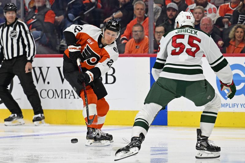 Oct 18, 2025; Philadelphia, Pennsylvania, USA; Philadelphia Flyers center Christian Dvorak (22) passes the puck against Minnesota Wild defenseman David Jiricek (55) during the first period at Wells Fargo Center. Mandatory Credit: Eric Hartline-Imagn Images