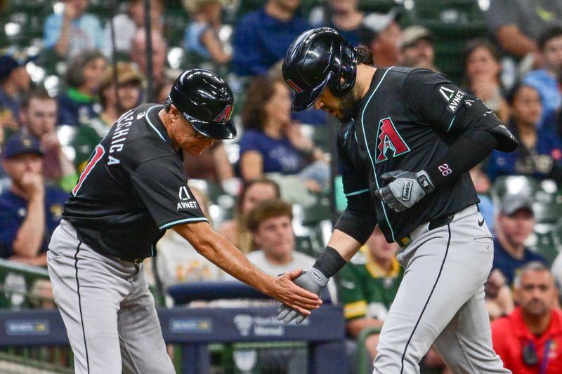 Sep 22, 2024; Milwaukee, Wisconsin, USA; Arizona Diamondbacks third baseman Eugenio Suarez (28) greets third base coach Tony Perezchica after hitting a solo home run in the third inning against the Milwaukee Brewers at American Family Field. Mandatory Credit: Benny Sieu-Imagn Images