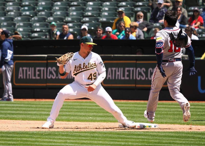 May 31, 2023; Oakland, California, USA; Oakland Athletics first baseman Ryan Noda (49) catches the ball ahead of Atlanta Braves catcher Travis d'Arnaud (16) during the seventh inning at Oakland-Alameda County Coliseum. Mandatory Credit: Kelley L Cox-USA TODAY Sports