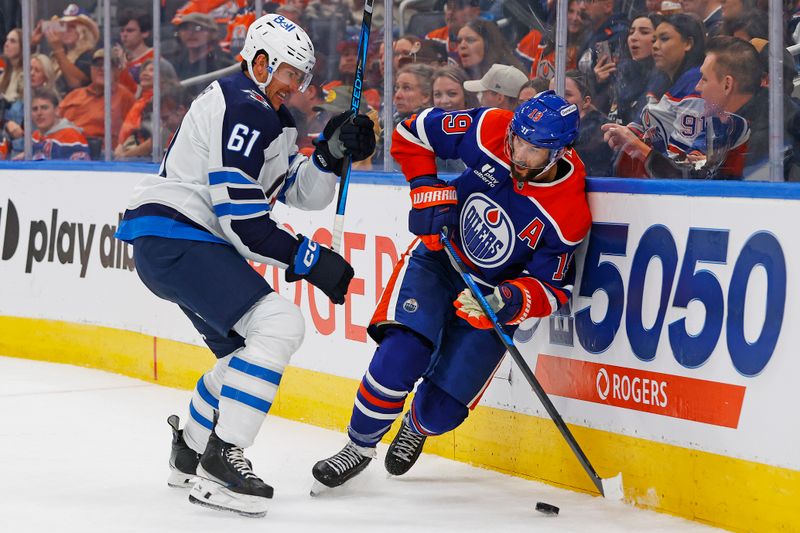 Sep 26, 2025; Edmonton, Alberta, CAN; Winnipeg Jets defensemen Ashton Sautner (61) and Edmonton Oilers forward Adam Henrique (19) battle along the boards for a loose puck during the third period at Rogers Place. Mandatory Credit: Perry Nelson-Imagn Images