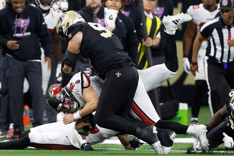 Tampa Bay Buccaneers quarterback Baker Mayfield, second from bottom, is tackled by New Orleans Saints defensive tackle Bryan Bresee during the second half of an NFL football game in New Orleans, Sunday, Oct. 13, 2024. (AP Photo/Butch Dill)