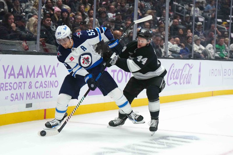 Nov 27, 2024; Los Angeles, California, USA; Winnipeg Jets center Mark Scheifele (55) and LA Kings defenseman Mikey Anderson (44) battle for the puck in the first period at Crypto.com Arena. Mandatory Credit: Kirby Lee-Imagn Images