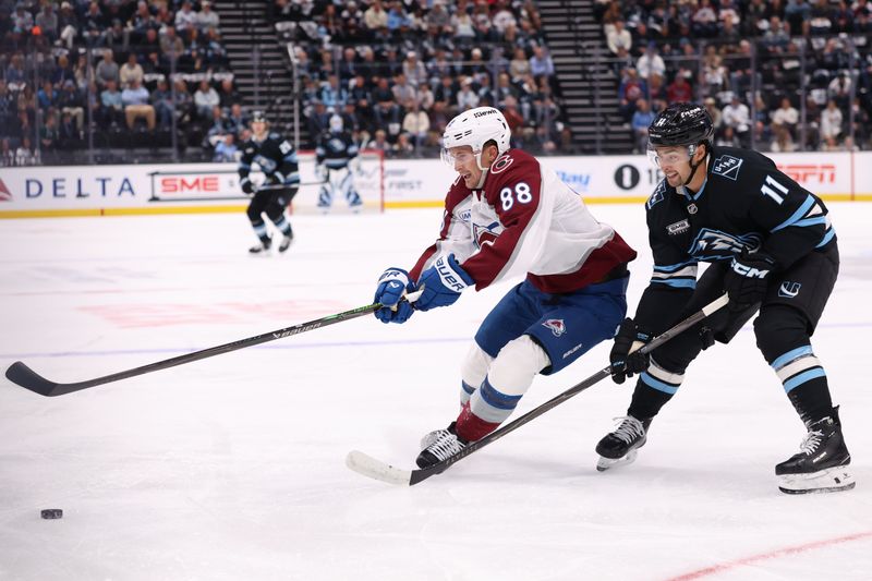 Oct 21, 2025; Salt Lake City, Utah, USA; Colorado Avalanche center Martin Necas (88) and Utah Mammoth right wing Dylan Guenther (11) battle for the puck during the first period at Delta Center. Mandatory Credit: Rob Gray-Imagn Images