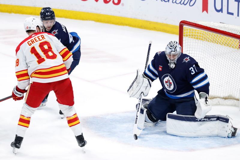 Apr 4, 2024; Winnipeg, Manitoba, CAN; Winnipeg Jets goaltender Connor Hellebuyck (37) blocks a shot by Calgary Flames left wing A.J. Greer (18) in the third period at Canada Life Centre. Mandatory Credit: James Carey Lauder-USA TODAY Sports