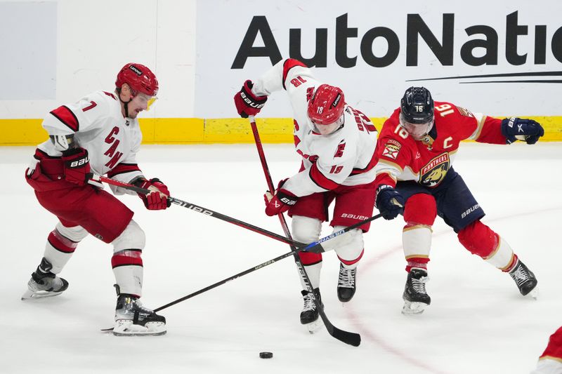 Nov 10, 2023; Sunrise, Florida, USA; Carolina Hurricanes defenseman Dmitry Orlov (7) and center Jack Drury (18) battle Florida Panthers center Aleksander Barkov (16) for the puck during the third period at Amerant Bank Arena. Mandatory Credit: Jasen Vinlove-USA TODAY Sports