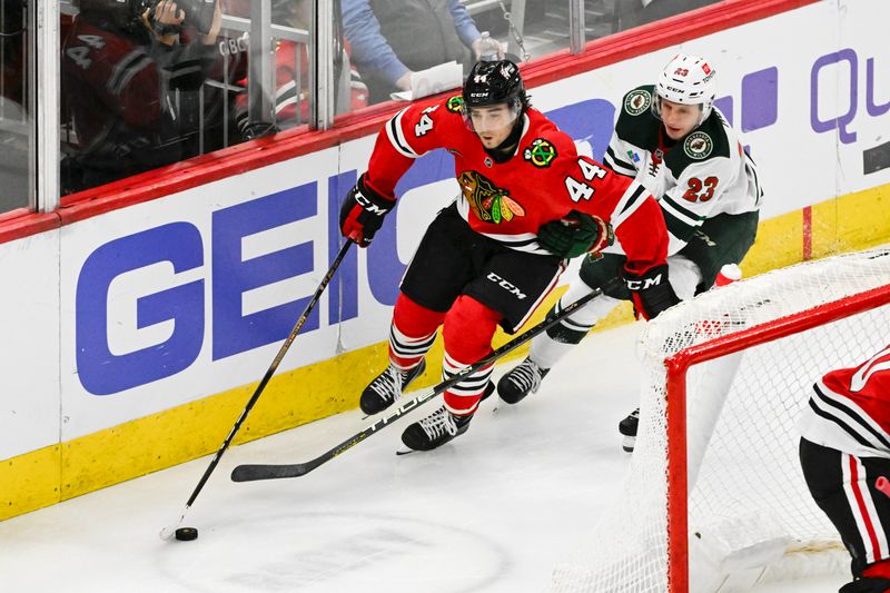 Apr 7, 2024; Chicago, Illinois, USA;  Chicago Blackhawks defenseman Wyatt Kaiser (44) and Minnesota Wild center Marco Rossi (23) chase the puck during the second period at United Center. Mandatory Credit: Matt Marton-USA TODAY Sports