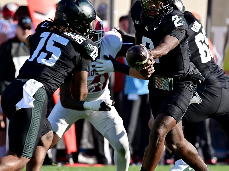 Nov 2, 2024; East Lansing, Michigan, USA;  Michigan State Spartans quarterback Aidan Chiles (2) hands the ball to Michigan State Spartans running back Kay'Ron Lynch-Adams (15) during the first quarter against the Indiana Hoosiers at Spartan Stadium. Mandatory Credit: Dale Young-Imagn Images