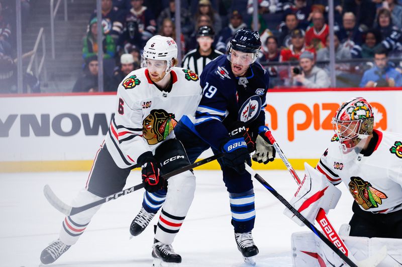 Oct 30, 2025; Winnipeg, Manitoba, CAN;  Winnipeg Jets forward Jonathan Toews (19) jostles for position with Chicago Blackhawks defenseman Sam Rinzel (6) during the second period at Canada Life Centre. Mandatory Credit: Terrence Lee-Imagn Images