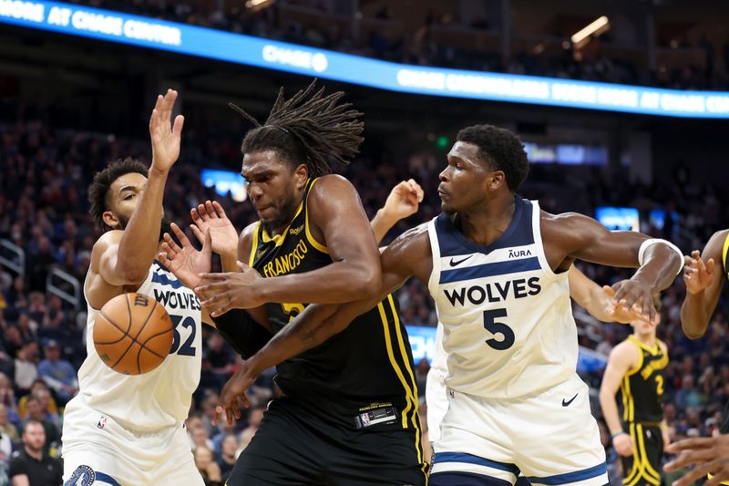 SAN FRANCISCO, CALIFORNIA - NOVEMBER 14: Kevon Looney #5 of the Golden State Warriors goes for a rebound against Karl-Anthony Towns #32 and Anthony Edwards #5 of the Minnesota Timberwolves at Chase Center on November 14, 2023 in San Francisco, California. NOTE TO USER: User expressly acknowledges and agrees that, by downloading and or using this photograph, User is consenting to the terms and conditions of the Getty Images License Agreement.  (Photo by Ezra Shaw/Getty Images)