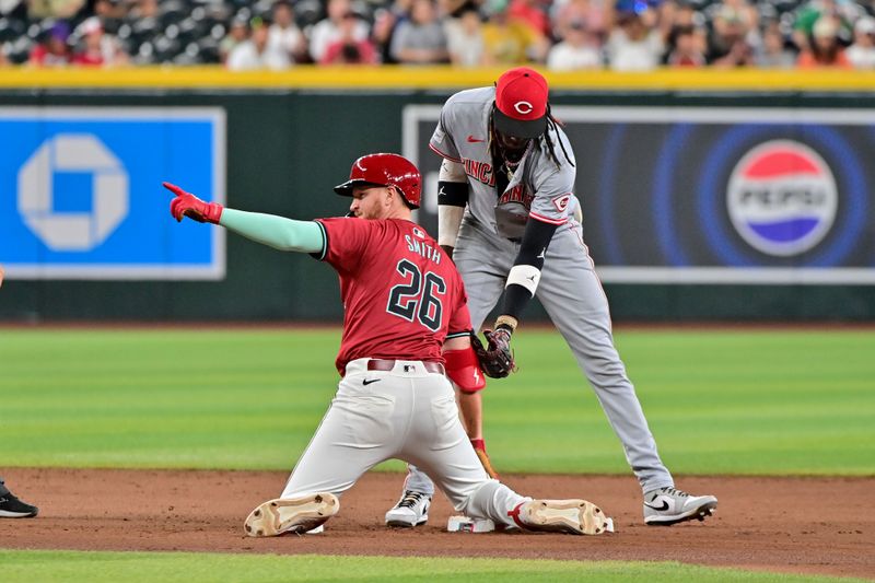 May 15, 2024; Phoenix, Arizona, USA;  Arizona Diamondbacks outfielder Pavin Smith (26) reacts after hitting a double in the eighth inning as Cincinnati Reds shortstop Elly De La Cruz (44) applies a late tag in the eighth inning at Chase Field. Mandatory Credit: Matt Kartozian-USA TODAY Sports