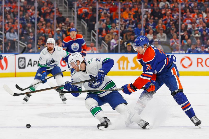 Apr 13, 2024; Edmonton, Alberta, CAN; Vancouver Canucks forward Nils Hoglander (21) and Edmonton Oilers forward Ryan McLeod (71) battle for a loose puck  during the third period at Rogers Place. Mandatory Credit: Perry Nelson-USA TODAY Sports