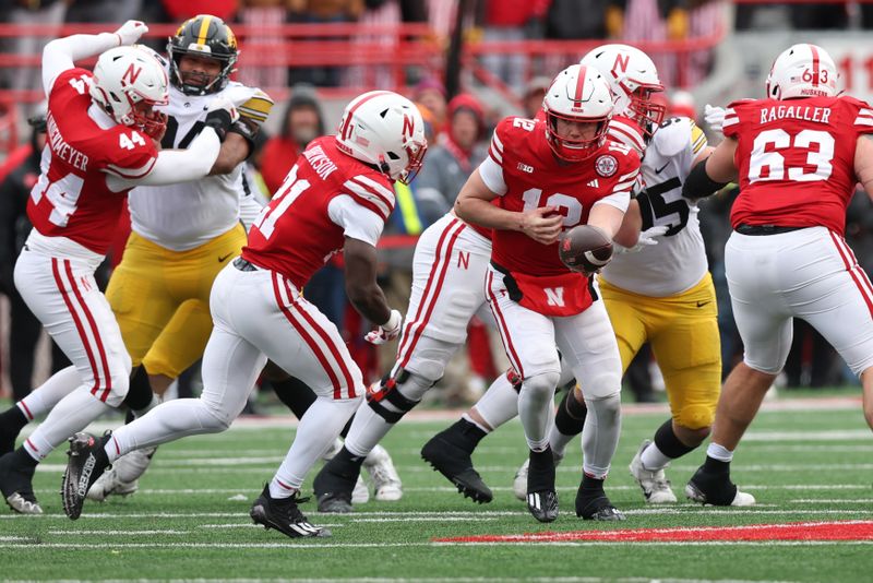 Nov 24, 2023; Lincoln, Nebraska, USA; Nebraska Cornhuskers quarterback Chubba Purdy (12) hands off to running back Emmett Johnson (21) during their game with the Iowa Hawkeyes at Memorial Stadium. Mandatory Credit: Reese Strickland-USA TODAY Sports