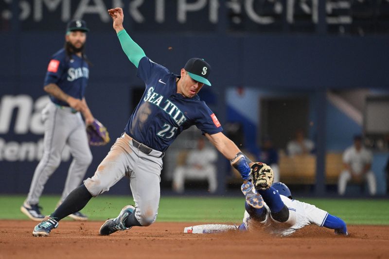 Apr 19, 2025; Toronto, Ontario, CAN;  Seattle Mariners second baseman Dylan Moore (25) tags out Toronto Blue Jays third baseman Ernie Clement (22) on an attempted steal of second base in the eighth inning at Rogers Centre. Mandatory Credit: Dan Hamilton-Imagn Images