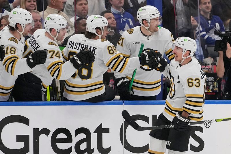 Apr 24, 2024; Toronto, Ontario, CAN; Boston Bruins forward Jake DeBrusk (74)  and  forward David Pastrnak (88) congratulate forward Brad Marchand (63) on his first goal of the game against the Toronto Maple Leafs during the third period of game three of the first round of the 2024 Stanley Cup Playoffs at Scotiabank Arena. Mandatory Credit: John E. Sokolowski-USA TODAY Sports