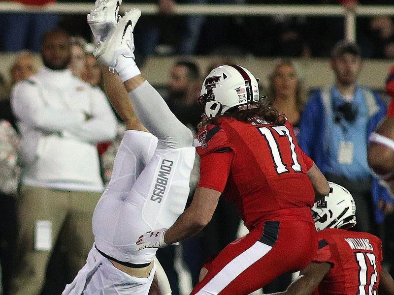 Nov 20, 2021; Lubbock, Texas, USA;  Oklahoma State Cowboys wide receiver Logan Carter (87) is tripped up by Texas Tech Red Raiders defensive corner back Rayshad Williams (12) in the first half at Jones AT&T Stadium. Mandatory Credit: Michael C. Johnson-USA TODAY Sports