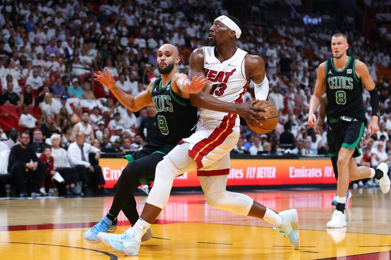 MIAMI, FLORIDA - APRIL 27: Bam Adebayo #13 of the Miami Heat drives against Derrick White #9 of the Boston Celtics during the third quarter in game three of the Eastern Conference First Round Playoffs at Kaseya Center on April 27, 2024 in Miami, Florida.  NOTE TO USER: User expressly acknowledges and agrees that, by downloading and or using this photograph, User is consenting to the terms and conditions of the Getty Images License Agreement. (Photo by Megan Briggs/Getty Images)