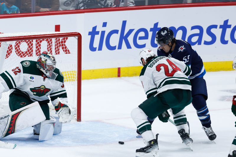 Oct 13, 2024; Winnipeg, Manitoba, CAN;  Winnipeg Jets forward Mark Scheifele (55) battles Minnesota Wild defenseman Zach Bogosian (24) for the puck in front of  Wild goalie Filip Gustavsson (32) during the third period at Canada Life Centre. Mandatory Credit: Terrence Lee-Imagn Images