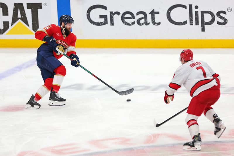 May 24, 2025; Sunrise, Florida, USA; Florida Panthers left wing Jonah Gadjovich (12) goes for the puck as Carolina Hurricanes defenseman Dmitry Orlov (7) defends during the second period in game three of the Eastern Conference Final of the 2025 Stanley Cup Playoffs at Amerant Bank Arena. Mandatory Credit: Sam Navarro-Imagn Images