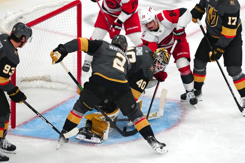 Oct 20, 2025; Las Vegas, Nevada, USA; Carolina Hurricanes center Seth Jarvis (24) looks for a rebound as Vegas Golden Knights defenseman Zach Whitecloud (2) and goaltender Akira Schmid (40) attempt to cover the puck during the third period at T-Mobile Arena. Mandatory Credit: Stephen R. Sylvanie-Imagn Images