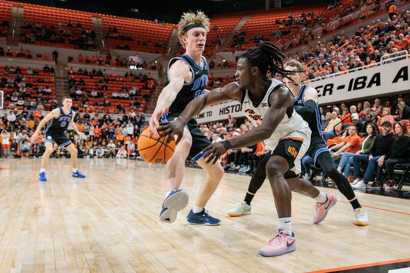 Feb 17, 2024; Stillwater, Oklahoma, USA; Oklahoma State Cowboys guard Javon Small (12) passes the ball around Brigham Young Cougars guard Richie Saunders (15) during the second half at Gallagher-Iba Arena. Mandatory Credit: William Purnell-USA TODAY Sports