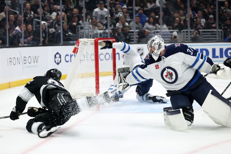 Apr 1, 2025; Los Angeles, California, USA;  Winnipeg Jets goaltender Connor Hellebuyck (37) trips Los Angeles Kings left wing Kevin Fiala (22) during the second period at Crypto.com Arena. Mandatory Credit: Kiyoshi Mio-Imagn Images