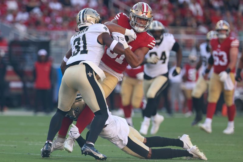 San Francisco 49ers tight end Cameron Latu, middle, runs against New Orleans Saints safety Jordan Howden (31) and cornerback Alontae Taylor, bottom, during the first half of a preseason NFL football game in Santa Clara, Calif., Sunday, Aug. 18, 2024. (AP Photo/Jed Jacobsohn)