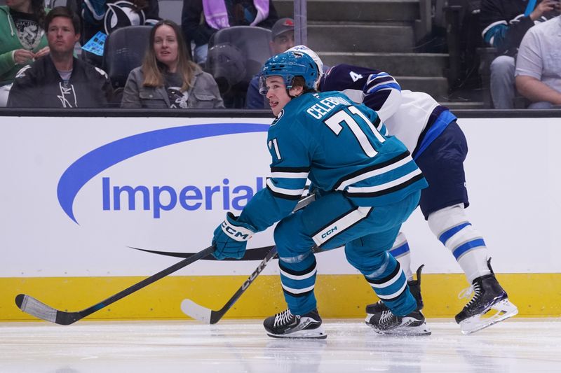 Nov 7, 2025; San Jose, California, USA; San Jose Sharks center Macklin Celebrini (71) and Winnipeg Jets defenseman Neal Pionk (4) (obscured) chase the puck in the first period at SAP Center at San Jose. Mandatory Credit: David Gonzales-Imagn Images