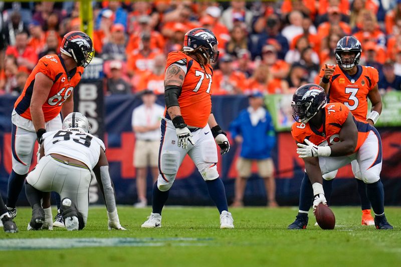 Denver Broncos quarterback Russell Wilson (3) signals as linemen Mike McGlinchey (69), Quinn Meinerz (77) and Lloyd Cushenberry III (79) look back against the Las Vegas Raiders during an NFL football game Sunday, Sept. 10, 2023, in Denver. (AP Photo/Jack Dempsey)