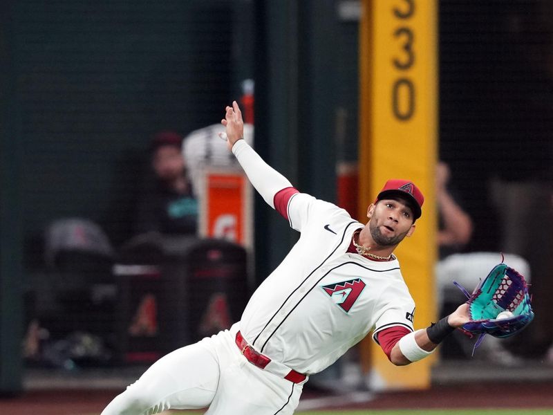 May 3, 2024; Phoenix, Arizona, USA; Arizona Diamondbacks outfielder Lourdes Gurriel Jr. (12) makes a sliding catch against the San Diego Padres during the fourth inning at Chase Field. Mandatory Credit: Joe Camporeale-USA TODAY Sports