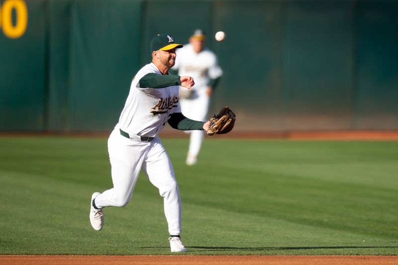 Jun 7, 2024; Oakland, California, USA; Oakland Athletics shortstop Max Schuemann (12) throws out Toronto Blue Jays first baseman Vladimir Guerrero Jr. at first base on a ground ball during the first inning at Oakland-Alameda County Coliseum. Mandatory Credit: D. Ross Cameron-USA TODAY Sports