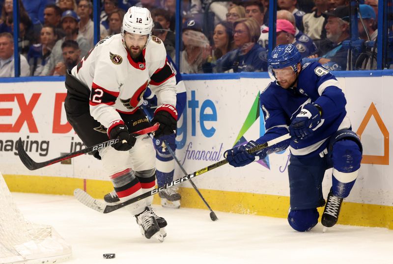 Apr 11, 2024; Tampa, Florida, USA; Ottawa Senators center Mark Kastelic (12) skates with the puck as Tampa Bay Lightning center Steven Stamkos (91) defends during the third period at Amalie Arena. Mandatory Credit: Kim Klement Neitzel-USA TODAY Sports