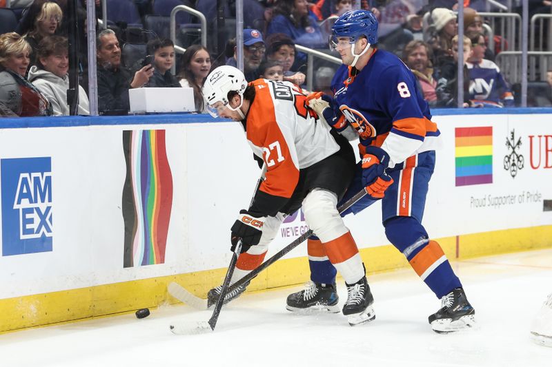 Jan 16, 2025; Elmont, New York, USA;  Philadelphia Flyers left wing Noah Cates (27) and New York Islanders defenseman Noah Dobson (8) battle for control of the puck in the first period at UBS Arena. Mandatory Credit: Wendell Cruz-Imagn Images