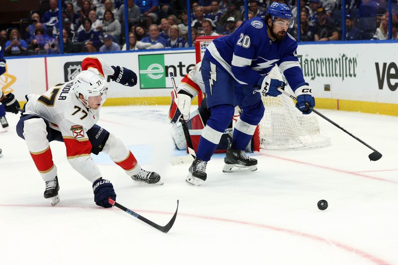 Apr 27, 2024; Tampa, Florida, USA; Tampa Bay Lightning left wing Nicholas Paul (20) passes the puck past Florida Panthers defenseman Niko Mikkola (77) during the third period in game four of the first round of the 2024 Stanley Cup Playoffs at Amalie Arena. Mandatory Credit: Kim Klement Neitzel-USA TODAY Sports