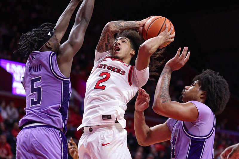 Feb 24, 2026; Piscataway, New Jersey, USA; Rutgers Scarlet Knights guard Lino Mark (2) goes to the basket against Washington Huskies guard Zoom Diallo (5) and center Lathan Sommerville (24) during the second half at Jersey Mike's Arena. Mandatory Credit: Vincent Carchietta-Imagn Images