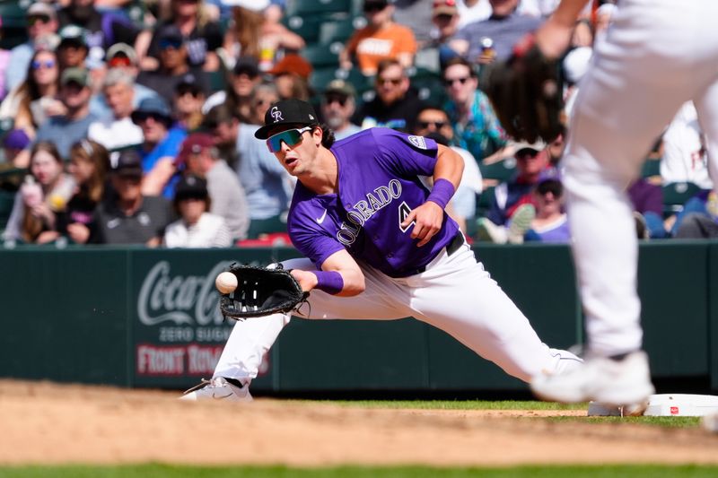 Apr 26, 2025; Denver, Colorado, USA; Colorado Rockies first base Michael Toglia (4) fields the ball in the sixth inning against the Cincinnati Reds at Coors Field. Mandatory Credit: Ron Chenoy-Imagn Images
