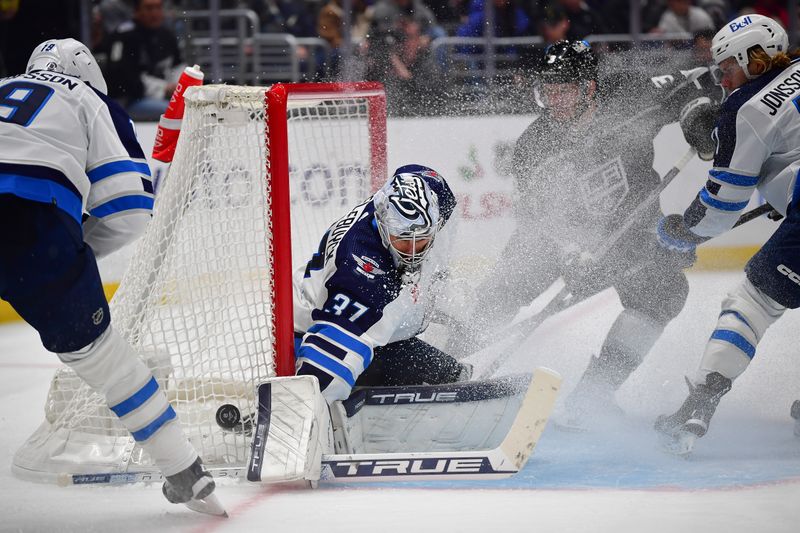 Dec 13, 2023; Los Angeles, California, USA; Winnipeg Jets goaltender Connor Hellebuyck (37) blocks a shot as Los Angeles Kings defenseman Matt Roy (3) moves in for the rebound during the second period at Crypto.com Arena. Mandatory Credit: Gary A. Vasquez-USA TODAY Sports