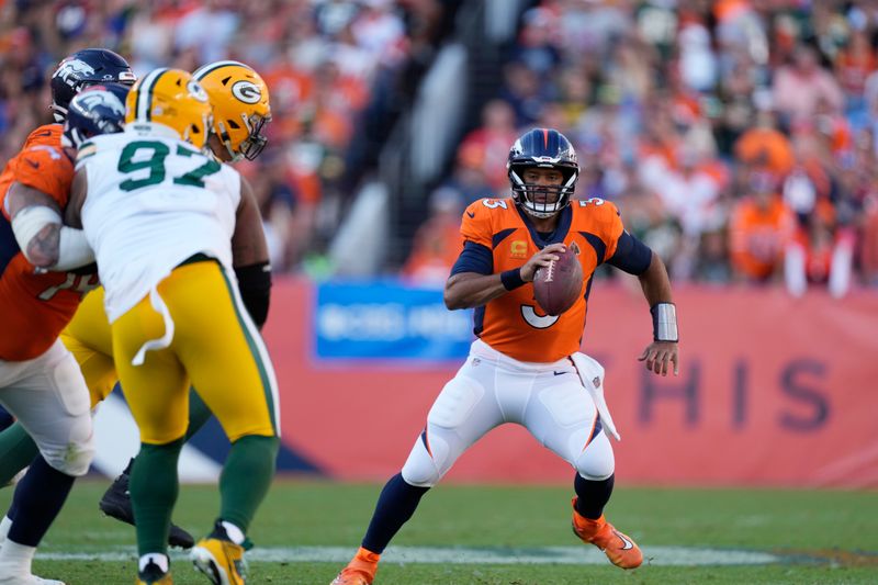 Denver Broncos quarterback Russell Wilson (3) evades Green Bay Packers defensive tackle Kenny Clark (97) in the second half of an NFL football game on Sunday, Oct. 22, 2023, in Denver. (AP Photo/David Zalubowski)