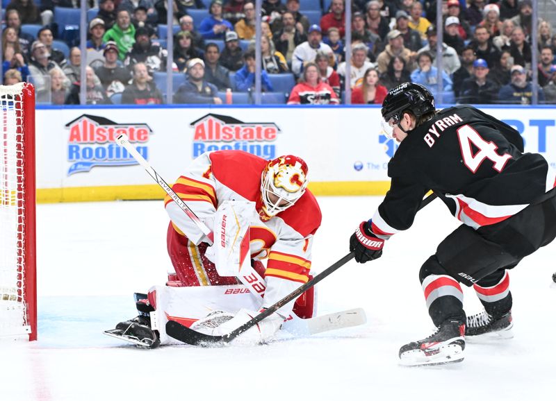 Nov 19, 2025; Buffalo, New York, USA; Calgary Flames goaltender Devin Cooley (1) blocks a shot by Buffalo Sabres defenseman Bowen Byram (4) in the second period at KeyBank Center. Mandatory Credit: Mark Konezny-Imagn Images