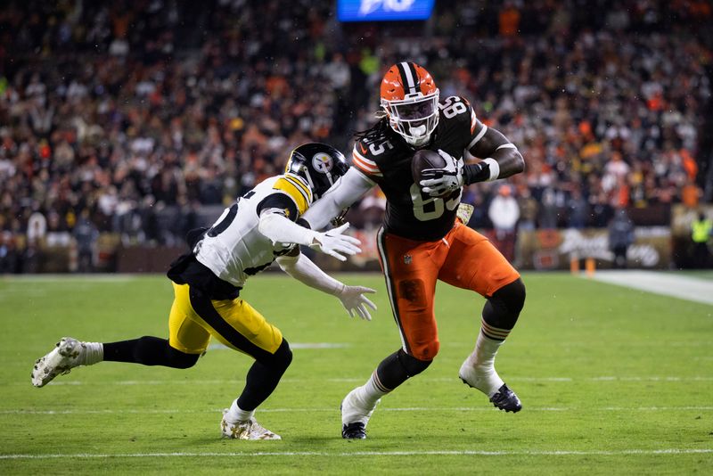 Cleveland Browns tight end David Njoku (85) attempts to break free from Pittsburgh Steelers safety DeShon Elliott (25) during an NFL football game, Thursday, Nov. 21, 2024, in Cleveland. (AP Photo/Matt Durisko)