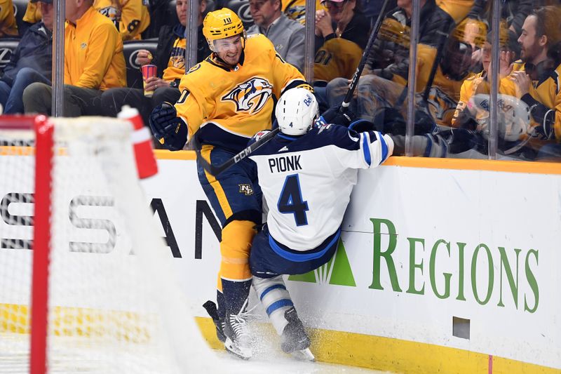 Apr 9, 2024; Nashville, Tennessee, USA; Nashville Predators center Colton Sissons (10) hits Winnipeg Jets defenseman Neal Pionk (4) during the third period at Bridgestone Arena. Mandatory Credit: Christopher Hanewinckel-USA TODAY Sports