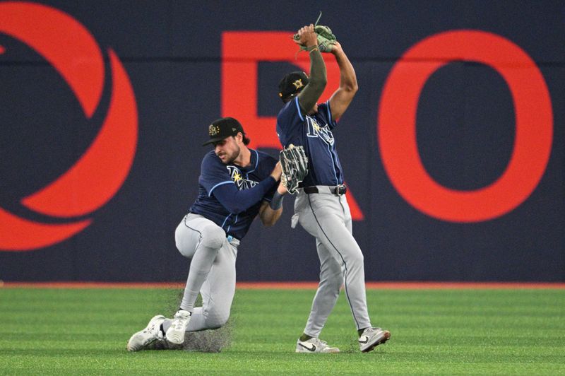 May 17, 2024; Toronto, Ontario, CAN;  Tampa Bay Rays right fielder Josh Lowe (15) turns to avoid colliding with center fielder Jonny DeLuca (21) who caught a fly ball hit by Toronto Blue Jays catcher Danny Jansen (not shown) in the fifth inning at Rogers Centre. Mandatory Credit: Dan Hamilton-USA TODAY Sports