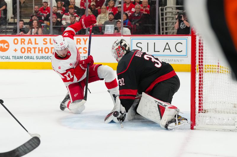 Dec 27, 2025; Raleigh, North Carolina, USA;  Carolina Hurricanes goaltender Brandon Bussi (32) stops the scoring attempt by Detroit Red Wings left wing J.T. Compher (37) during the second period at Lenovo Center. Mandatory Credit: James Guillory-Imagn Images