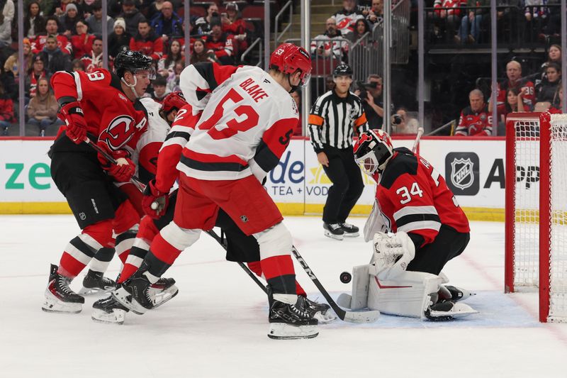 Jan 4, 2026; Newark, New Jersey, USA; New Jersey Devils goaltender Jake Allen (34) makes a save as Carolina Hurricanes right wing Jackson Blake (53) looks for the puck during the first period at Prudential Center. Mandatory Credit: Ed Mulholland-Imagn Images