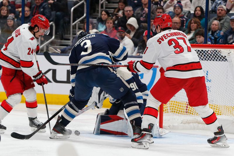 Dec 31, 2024; Columbus, Ohio, USA; Columbus Blue Jackets defenseman Jack Johnson (3) and Carolina Hurricanes center Seth Jarvis (24) battle for a loose puck from a goalie Elvis Merzlikins (90) sat during the second period at Nationwide Arena. Mandatory Credit: Russell LaBounty-Imagn Images