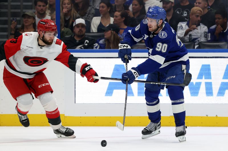 Sep 26, 2025; Tampa, Florida, USA; Tampa Bay Lightning defenseman J.J. Moser (90) passes the puck as Carolina Hurricanes left wing Gleb Trikozov (73) defends during the second period at Benchmark International Arena. Mandatory Credit: Kim Klement Neitzel-Imagn Images