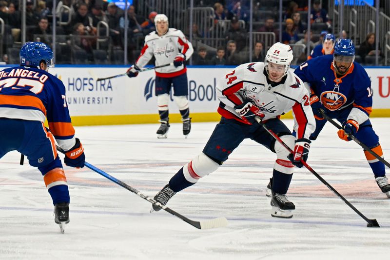 Nov 30, 2025; Elmont, New York, USA;  Washington Capitals center Connor McMichael (24) skates across the blue line defended by New York Islanders defenseman Tony Deangelo (77) during the first period at UBS Arena. Mandatory Credit: Dennis Schneidler-Imagn Images
