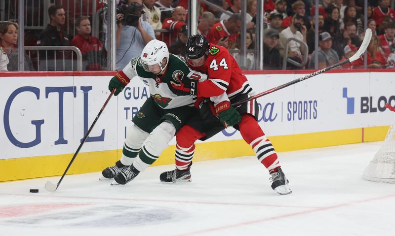 Oct 3, 2025; Chicago, Illinois, USA; Minnesota Wild left wing Marcus Johansson (90) and Chicago Blackhawks defenseman Wyatt Kaiser (44) battle for control of the puck during the second period at United Center. Mandatory Credit: Talia Sprague-Imagn Images